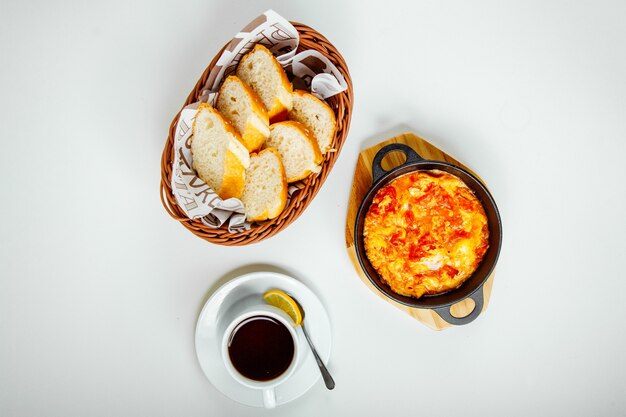 des œufs brouillés avec des tomates, du pain et une tasse de thé