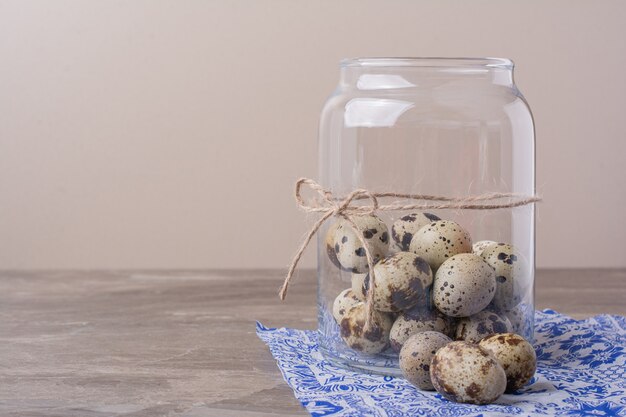 Oeufs de caille dans un pot contenant sur la serviette bleue