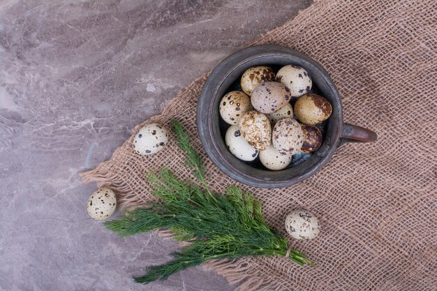 Oeufs de caille dans un pot métallique sur morceau de toile de jute.