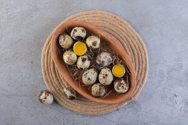 Oeufs de caille frais crus placés sur une surface en pierre.