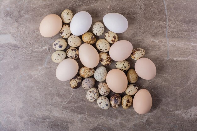 Oeufs de caille et de poule isolés sur table en marbre.