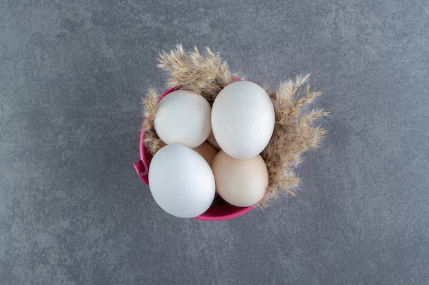 Oeufs crus biologiques dans un bol rose.