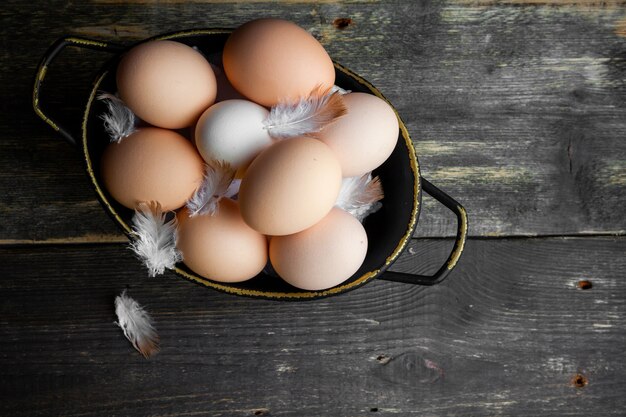 Oeufs dans un pot avec des plumes vue de dessus sur un fond en bois foncé