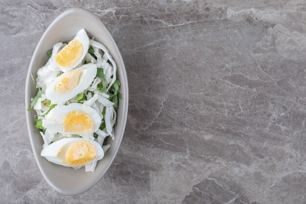 Oeufs durs et salade fraîche dans un bol en céramique.