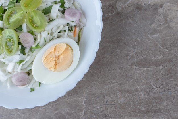 Oeufs durs et salade fraîche sur plaque blanche.