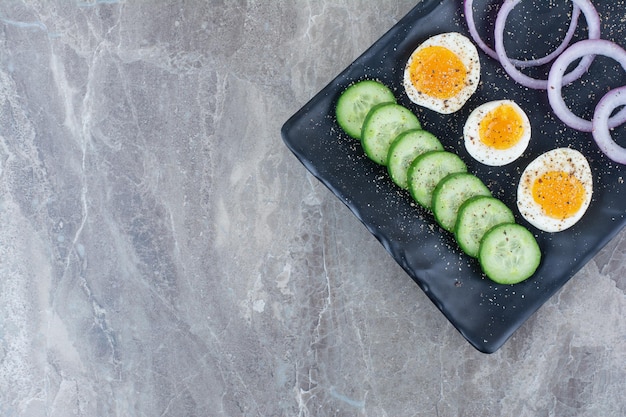 Oeufs durs savoureux avec des épices et des légumes sur une assiette noire. photo de haute qualité