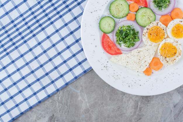 Oeufs durs savoureux avec des épices et des légumes sur une nappe. photo de haute qualité