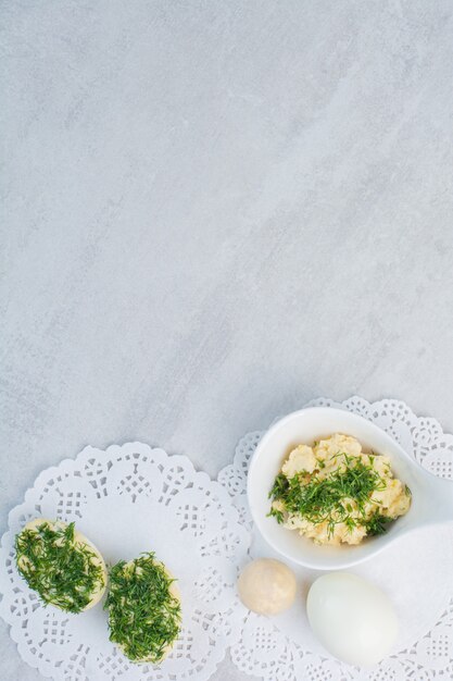 Oeufs durs avec des verts sur fond blanc.