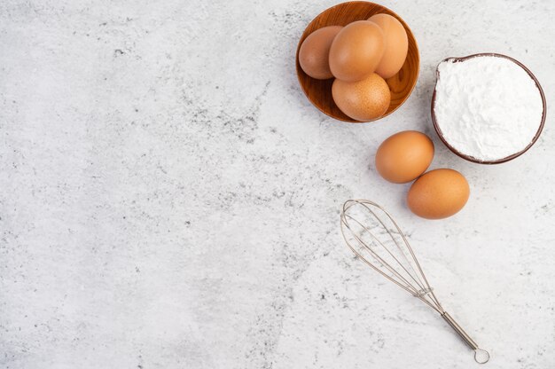 Oeufs, farine de tapioca dans une tasse et batteur à oeufs.