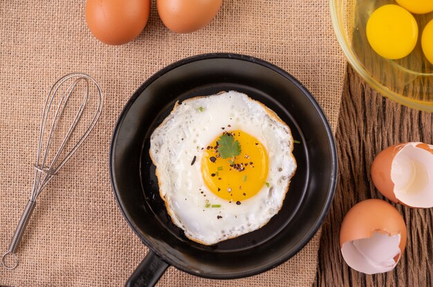 Oeufs frits dans une poêle et oeufs crus, aliments biologiques pour une bonne santé, riches en protéines