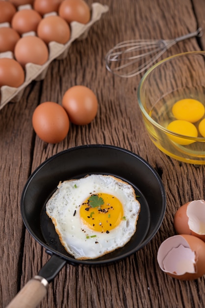 Oeufs frits dans une poêle et oeufs crus, aliments biologiques pour une bonne santé, riches en protéines