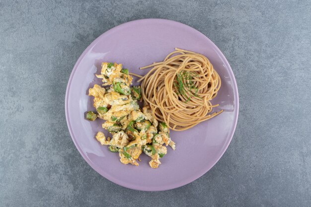 Oeufs frits avec spaghetti sur plaque violette.