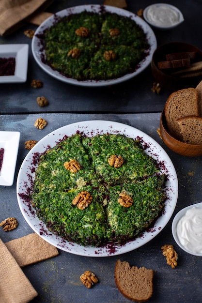 Photo gratuite oeufs avec kuku verts riches en vitamines savoureux avec des noix conçues sur un bureau gris