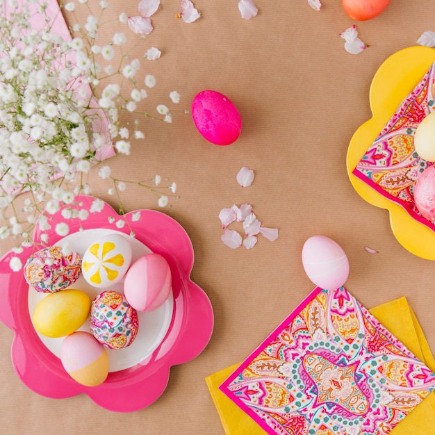 Photo gratuite oeufs de pâques sur une assiette près des serviettes et des fleurs