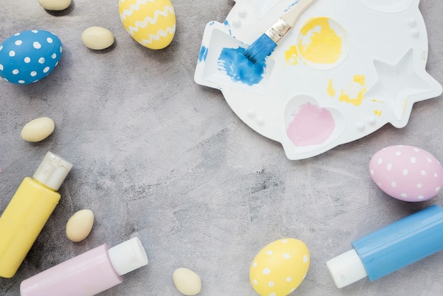 Oeufs de Pâques avec des bâtons de colle et de la palette de peinture sur la table