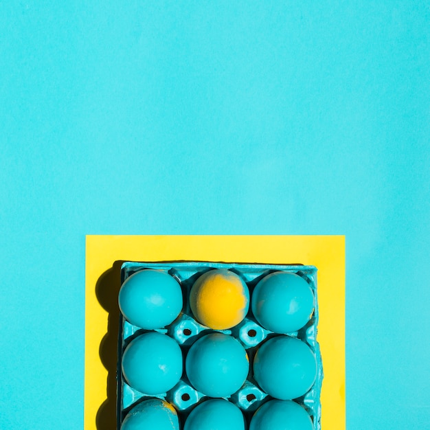 Oeufs de Pâques colorés dans le rack dans le cadre sur la table bleue