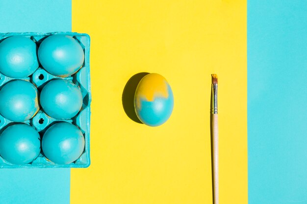 Oeufs de Pâques colorés dans un rack avec un pinceau sur la table