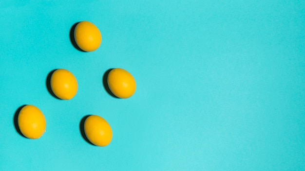 Oeufs de Pâques colorés dispersés sur la table bleue