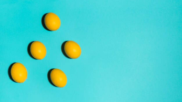 Oeufs de Pâques colorés dispersés sur la table bleue