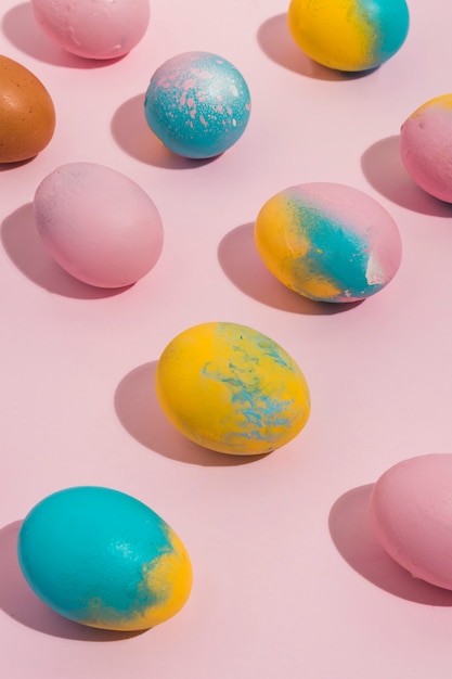 Oeufs de Pâques colorés dispersés sur une table rose