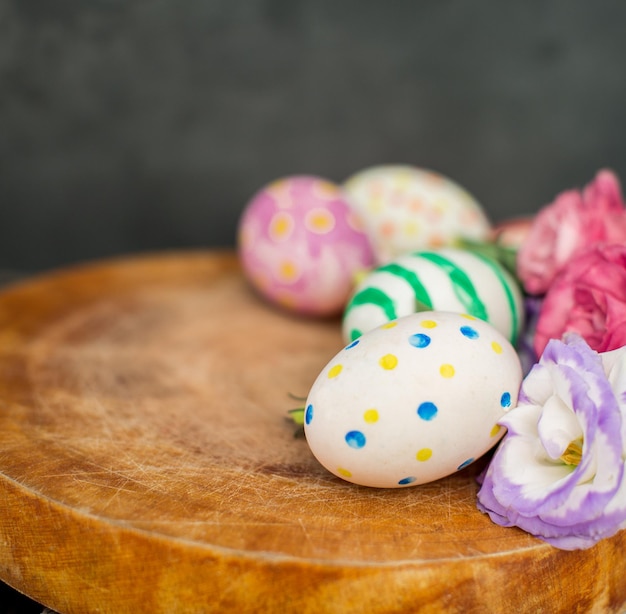 Photo gratuite oeufs de pâques colorés et lisianthus sur table en bois