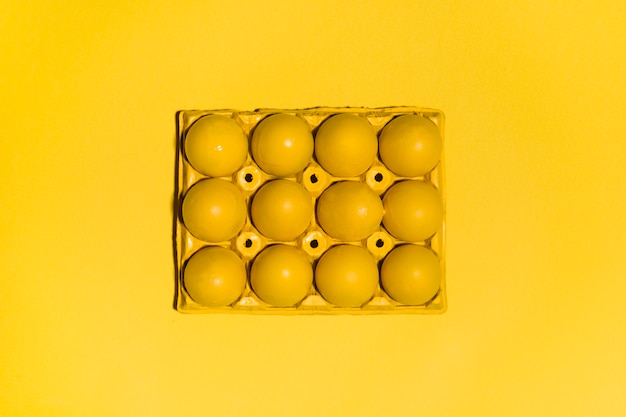 Oeufs de Pâques colorés en rack sur une table jaune