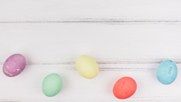 Photo gratuite oeufs de pâques colorés sur une table en bois