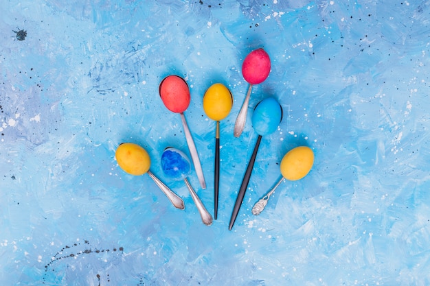 Photo gratuite oeufs de pâques en cuillères sur la table bleue