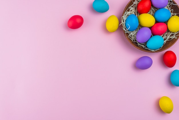 Photo gratuite oeufs de pâques dans un bol sur la table rose