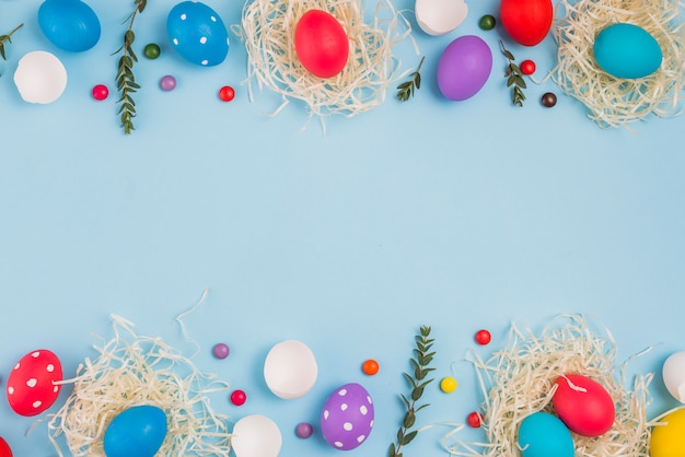 Oeufs de Pâques dans des nids avec des branches de plantes et des bonbons