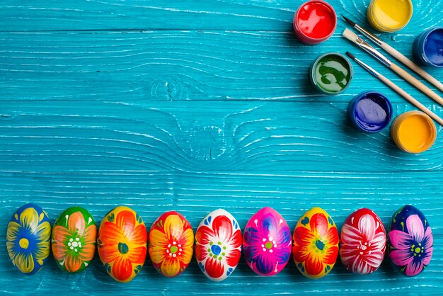 oeufs de Pâques dans la rangée avec pinceaux et pots de peinture