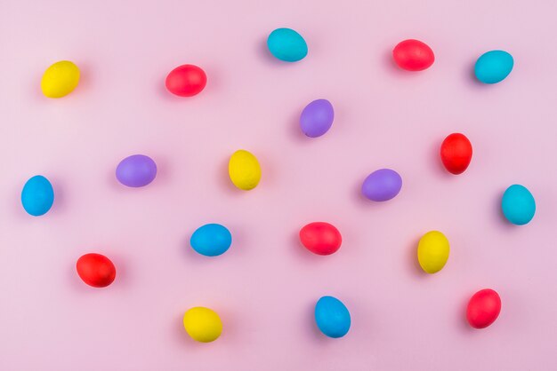 Oeufs de Pâques dispersés sur une table rose