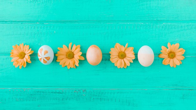 Oeufs de Pâques et fleurs orange sur le bureau