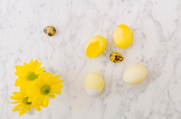 Oeufs de Pâques jaunes près de fleurs fraîches