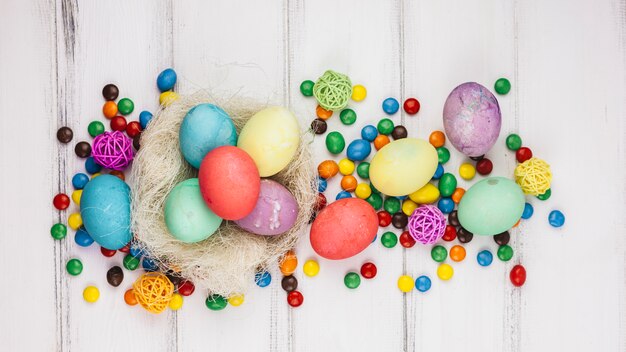 Oeufs de Pâques en nid avec des bonbons sur une table en bois