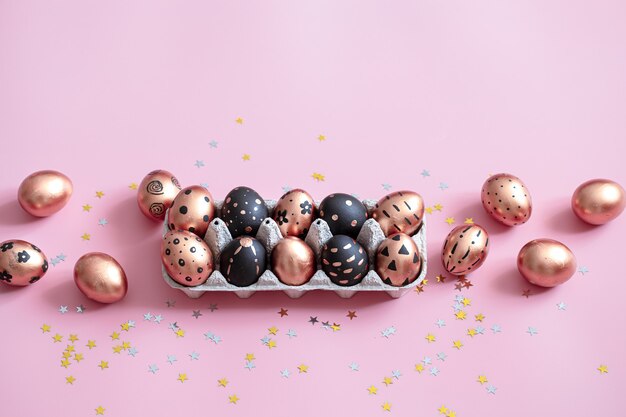 Oeufs de Pâques peints de fête sur mur rose.