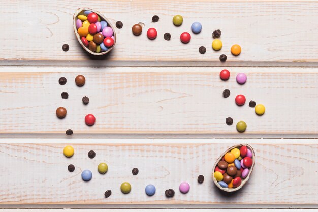 Oeufs de Pâques remplis de bonbons colorés sur un bureau en bois avec un espace au centre pour l&#39;écriture du texte