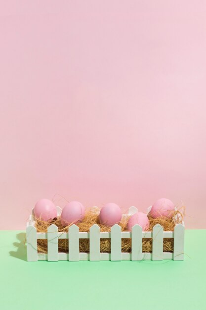 Photo gratuite oeufs de pâques roses sur le foin en boîte sur la table