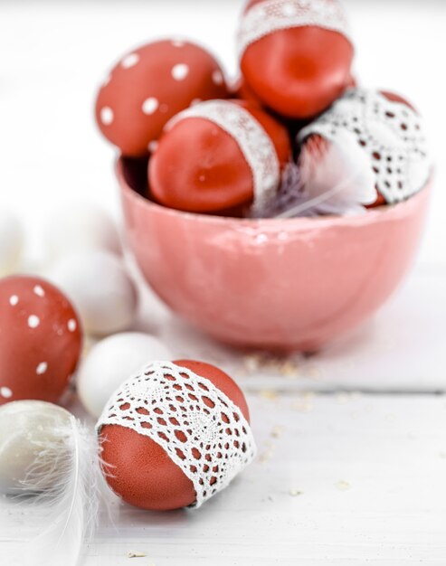 Oeufs de Pâques rouges sur ruban de dentelle attaché blanc, gros plan