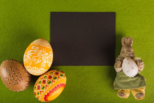 Oeufs de Pâques et la statuette de lapin près de papier