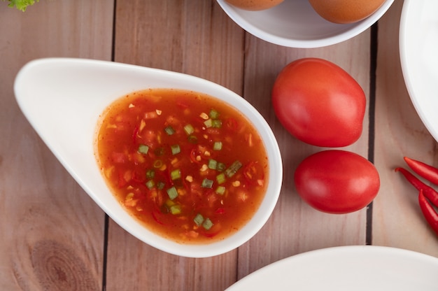 Oeufs, piment, tomate et sauce dans une assiette blanche sur un bois.