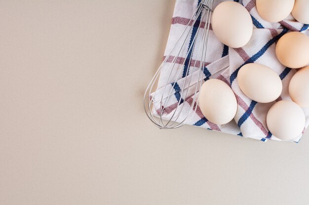 Oeufs de poule blancs crus frais placés sur une table beige.