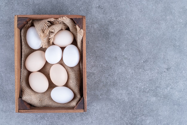 Oeufs de poule blancs frais sur un panier en bois