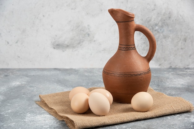 Oeufs de poule crus frais et bouteille antique sur une surface en marbre.