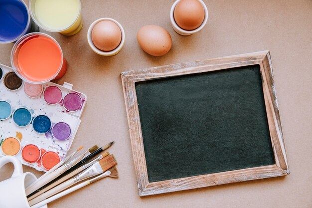 Oeufs et tableau noir sur la table avec des peintures