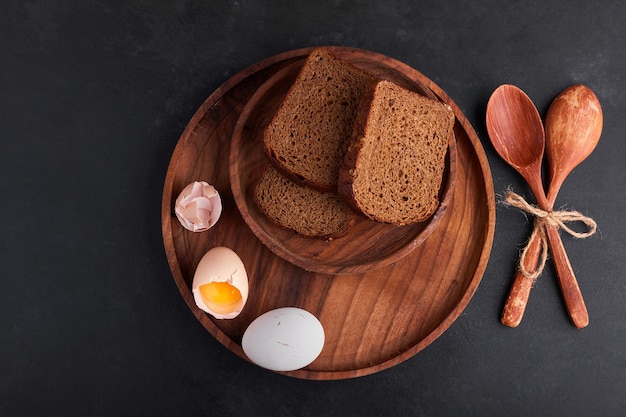 Oeufs avec des tranches de pain dans un plateau en bois, vue du dessus.