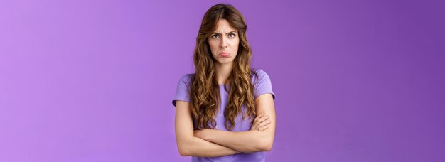 Offendue bête timide mignonne fille bourdonnante lèvres grinçantes fronçant les sourcils gémissant bouleversée mains croisées pose de bloc