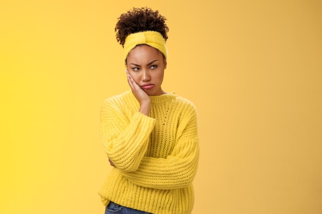 Photo gratuite offensé sombre boudeur grincheux jeune petite amie afro-américaine se sentir irrité jaloux fronçant les sourcils dérangé bouder détourner le regard insulté ne veut pas parler quelqu'un maigre tête de main debout fond jaune.