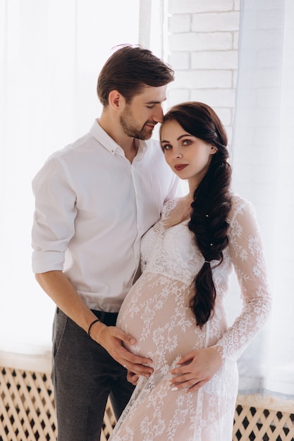 Offres câlins de jeune couple attend debout dans studio lumineux