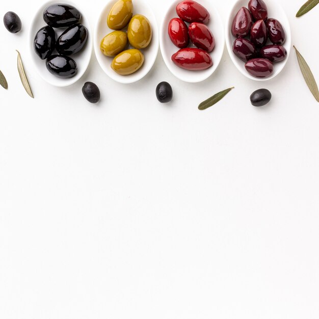 Olives pourpres jaunes rouges noires sur des assiettes avec espace de copie